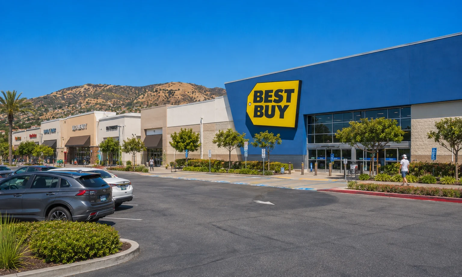 Savi Ranch Yorba Linda. The Best Buy anchor and adjacent retail shops, with surface parking and the Santa Ana Mountains behind. Southern California retail developer.