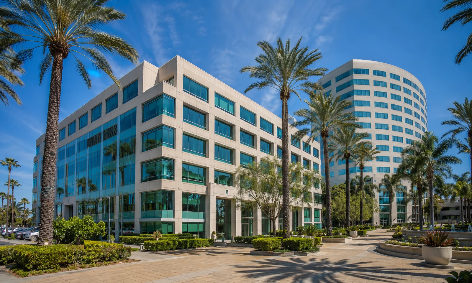 Stadium Towers Plaza Anaheim. The four-story office building beside the curved tower, framed by palms in the Platinum Triangle. Anaheim commercial real estate.